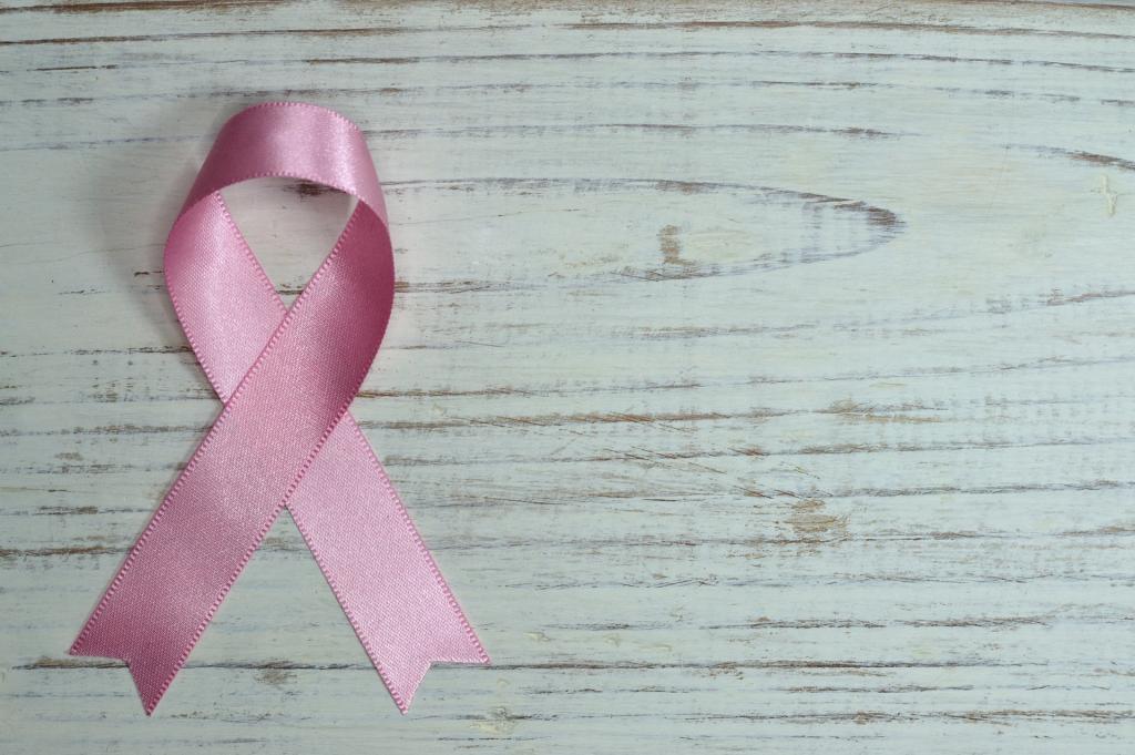 A pink breast cancer awareness ribbon on a wooden table